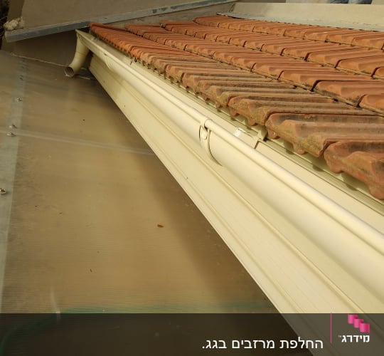 רעפים חומים על גג עם מרזב לבן